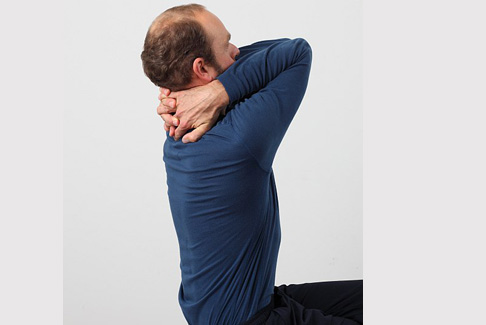 Die Arme hinter dem Kopf im Nacken verschränken. Dann die Ellenbogen nach oben drücken und dort kurz halten. Diese Übung kann bis zu 15 mal wiederholt werden. 