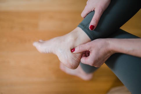 Frau mit Schmerzen in der Achillessehne beim Joggen