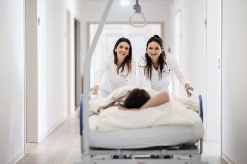 Krankenpflegerinnen schieben ein Bett
