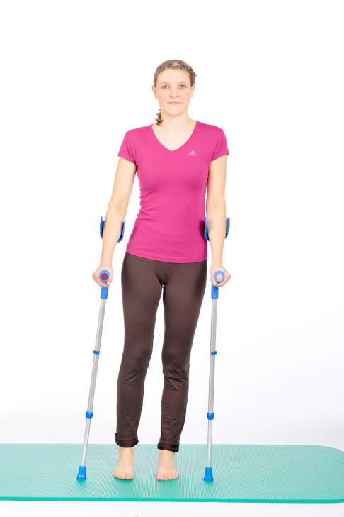Frau im Stand mit Krücken, Gewicht auf dem linken Bein.