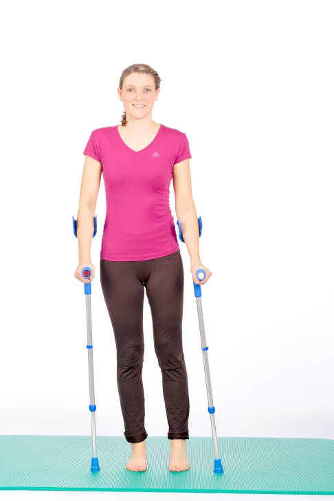 Frau im Stand mit Krücken, Gewicht auf dem rechten Bein.