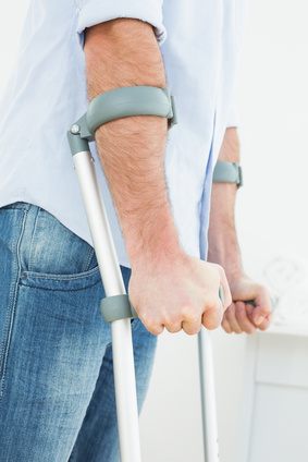 Patient mit Unterarmgehstützen zur Entlastung des Kniegelenks nach Außenbandriss