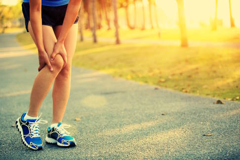 Frau mit Schmerzen im Kniegelenk beim Laufen