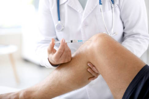 Arzt injiziert Glukoselösung ins Kniegelenk