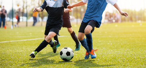 Drei Fussballer mit Ball auf dem Spielfeld