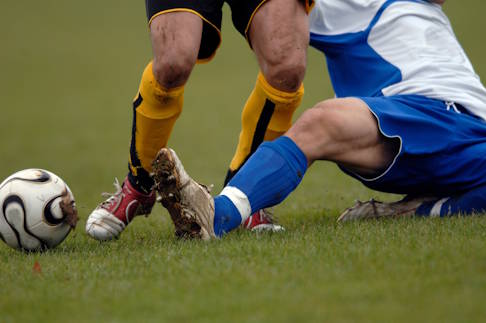 Besonders gefährdet für eine Adduktorenzerrung sind Menschen, die Sportarten mit schnellen Richtungswechseln und abrupten Stopps ausüben. © karaboux, Adobe Fußballer verletzt sich