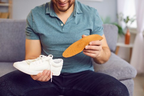 Orthopädische Schuheinlagen helfen bei einer Vielzahl von Fußproblemen. Damit sie ihre Wirkung entfalten, müssen sie allerdings gut in den Schuh passen. ©Studio Romantic, Adobe Patient setzt Schuheinlage ein
