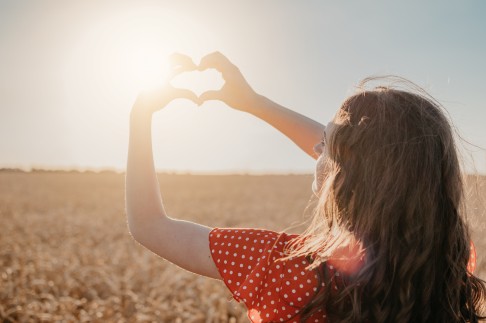 Frau hält ihre Arme und ihr Gesicht in die Sonne.